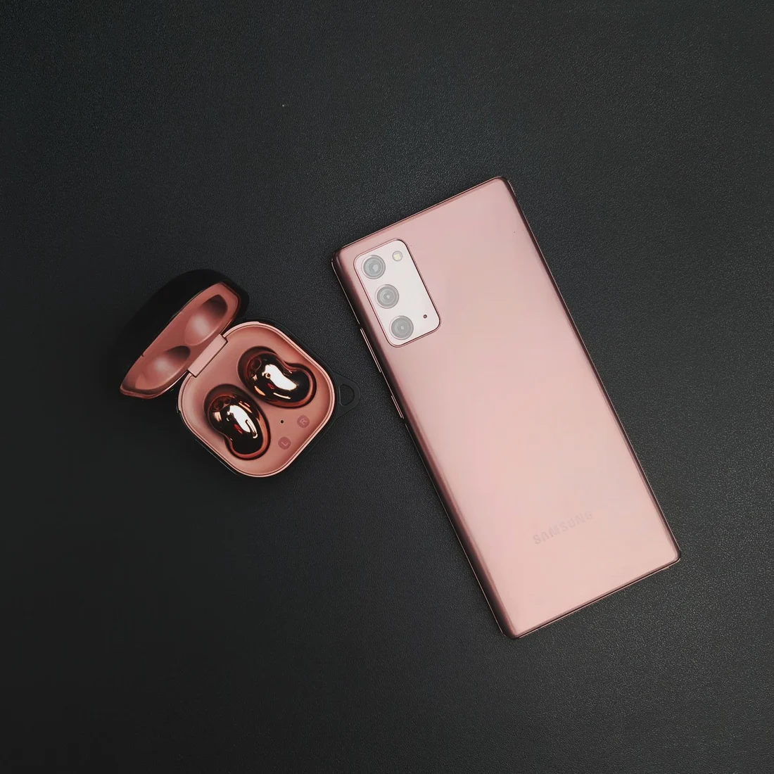 Smartphone e fones sem fio sobre superfície escura